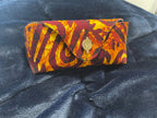 Colorful patterned clutch bag on a dark blue denim surface