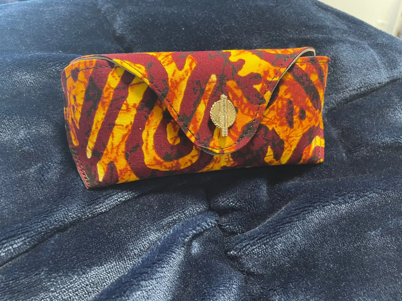 Colorful patterned clutch bag on a dark blue denim surface