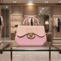 Pink handbag with a gold emblem on a white background