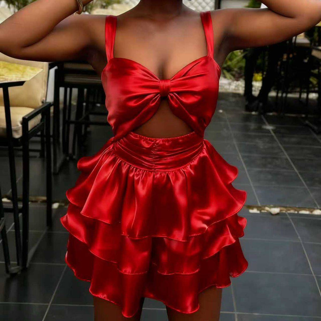 Woman wearing a red satin dress with a bow detail in an outdoor setting.