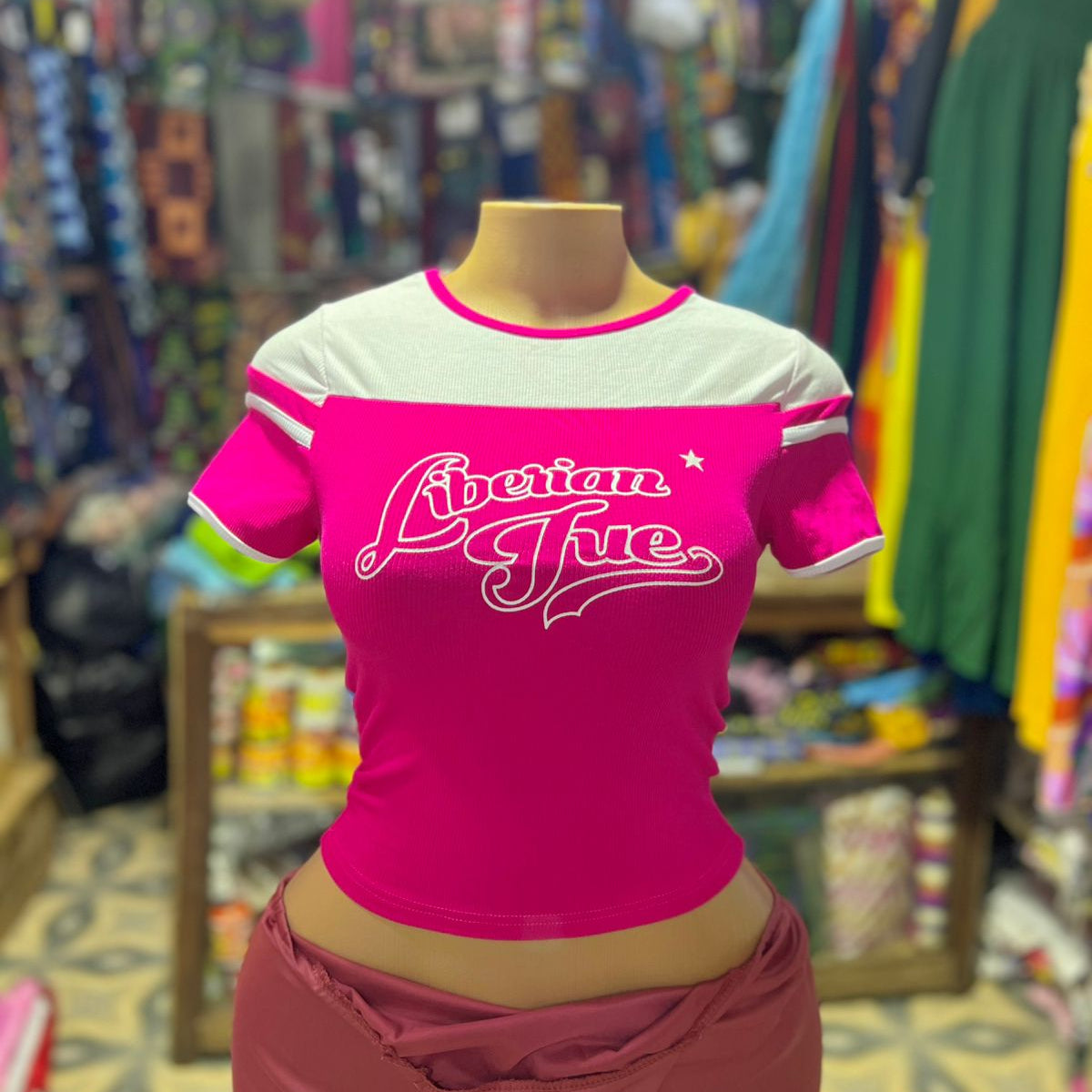 Pink and white t-shirt with 'American Pie' text on a mannequin in a store setting.