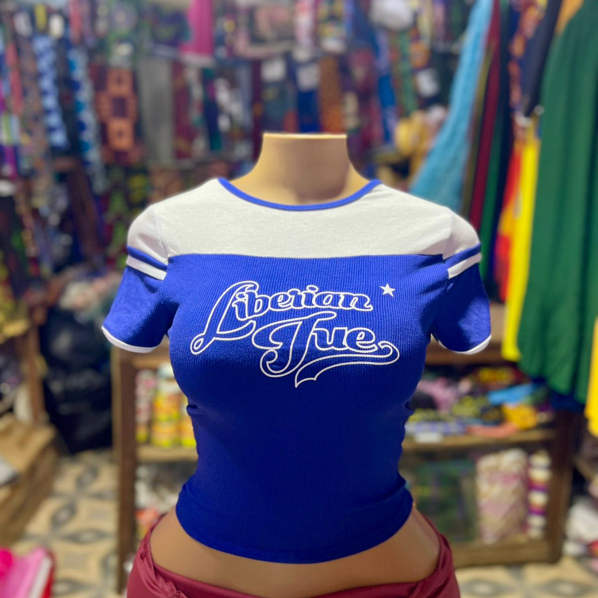 Blue and white shirt with 'Libertine' text on a mannequin in a colorful store setting.