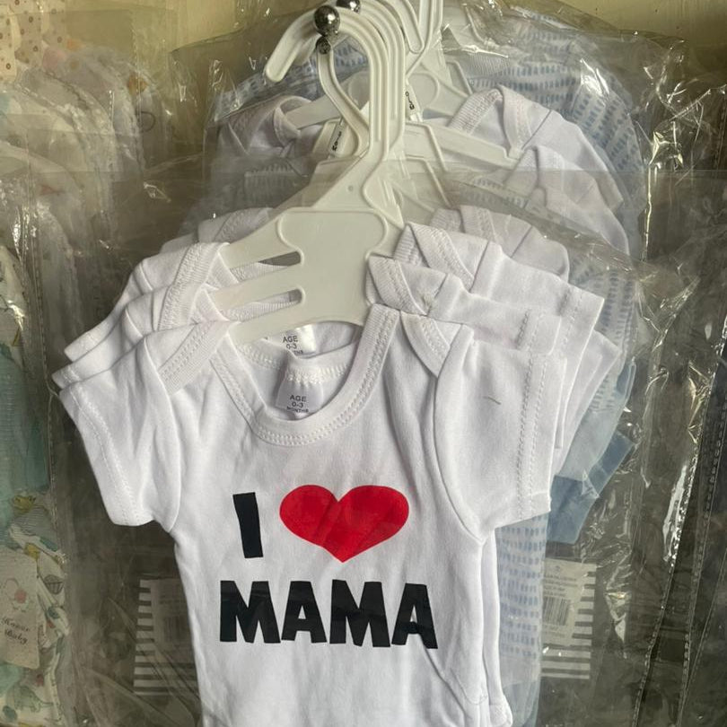 White baby onesie with 'I ❤️ MAMA' text on a hanger.