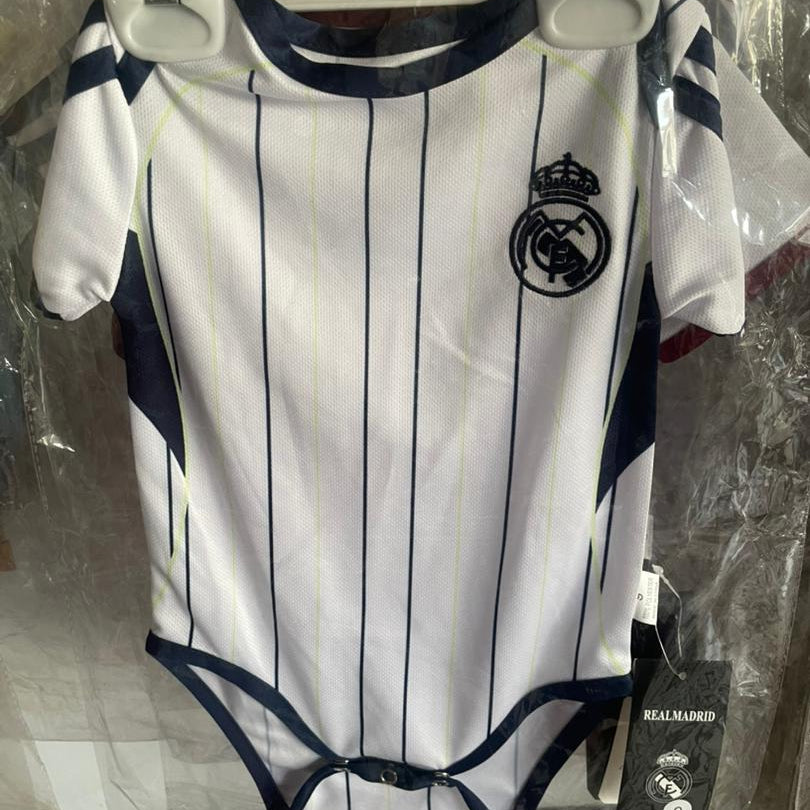 White and navy striped baby onesie with Real Madrid logo on a hanger.