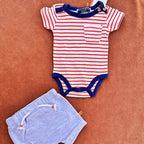 Striped baby bodysuit and shorts set on a brown surface