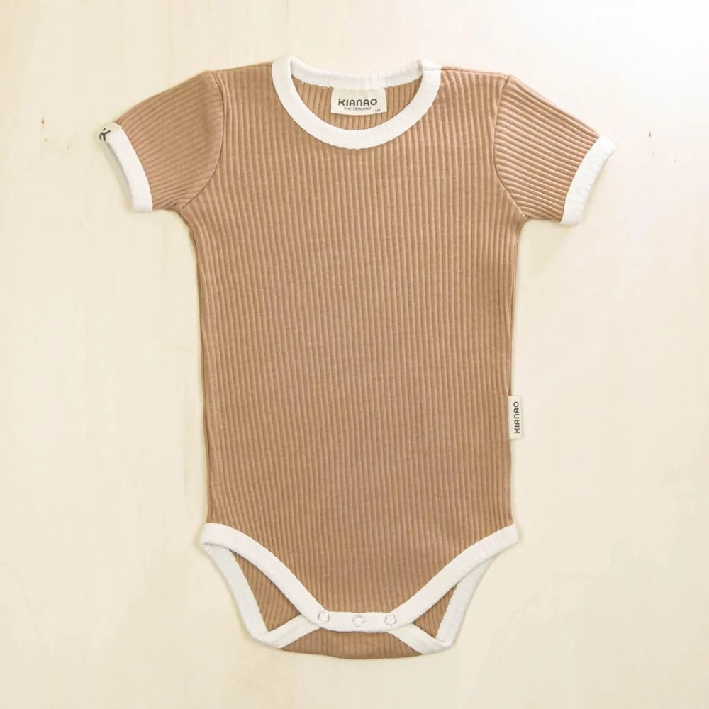 Brown ribbed baby onesie with white trim on a beige background