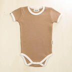 Brown ribbed baby onesie with white trim on a beige background