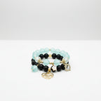 Beaded bracelet with black, blue, and gold beads on a reflective surface