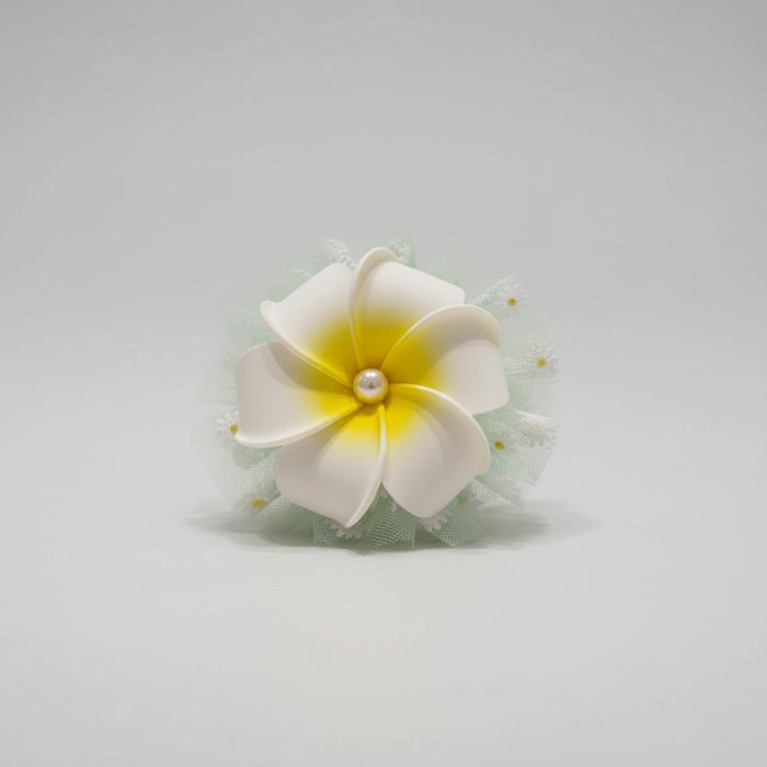 Floral hair clip with white and yellow flower on a reflective surface