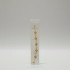 Gold bracelet on a clear plastic card with brand name, on a reflective surface.