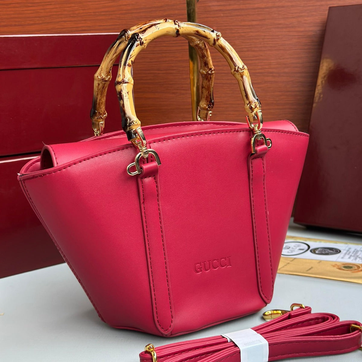 Red Gucci handbag with gold bamboo handle on a wooden surface