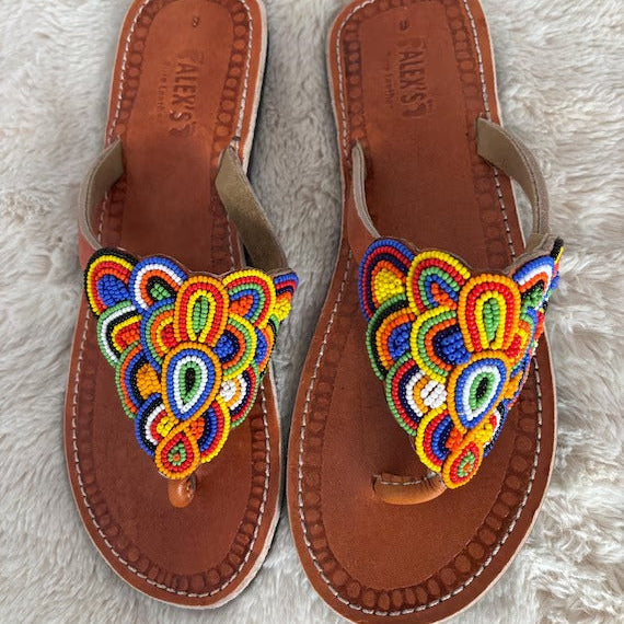 Pair of brown sandals with colorful embroidered designs on a light gray background