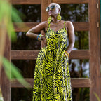Woman wearing a yellow and black zebra print dress standing in front of a wooden door.