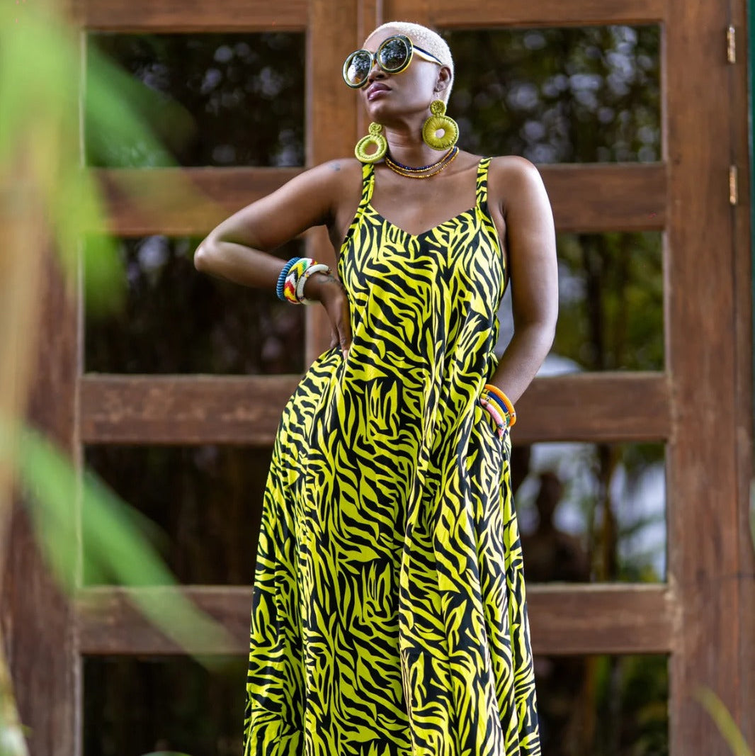 Woman wearing a yellow and black zebra print dress standing in front of a wooden door.