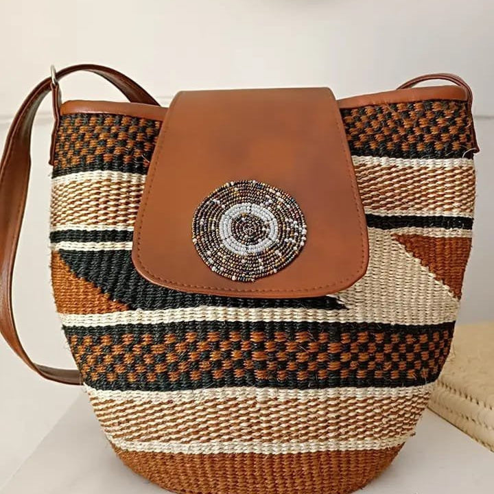 Woven handbag with brown leather accents and decorative button on a light background