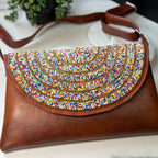 Brown handbag with colorful bead design on a marble surface
