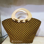 Black and yellow patterned handbag with wooden handle on a white background