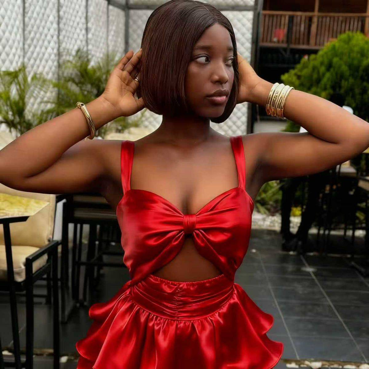 Woman wearing a red satin dress with a bow detail in an outdoor setting.
