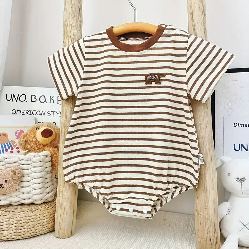 Striped baby romper with brown accents hanging on a wooden hanger against a neutral background.