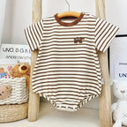 Striped baby romper with brown accents hanging on a wooden hanger against a neutral background.