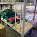 Bunk bed with mattresses and bedding in a storage or warehouse setting
