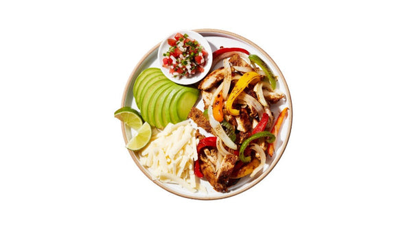 Platter of fajitas with vegetables and a side of salsa on a white background
