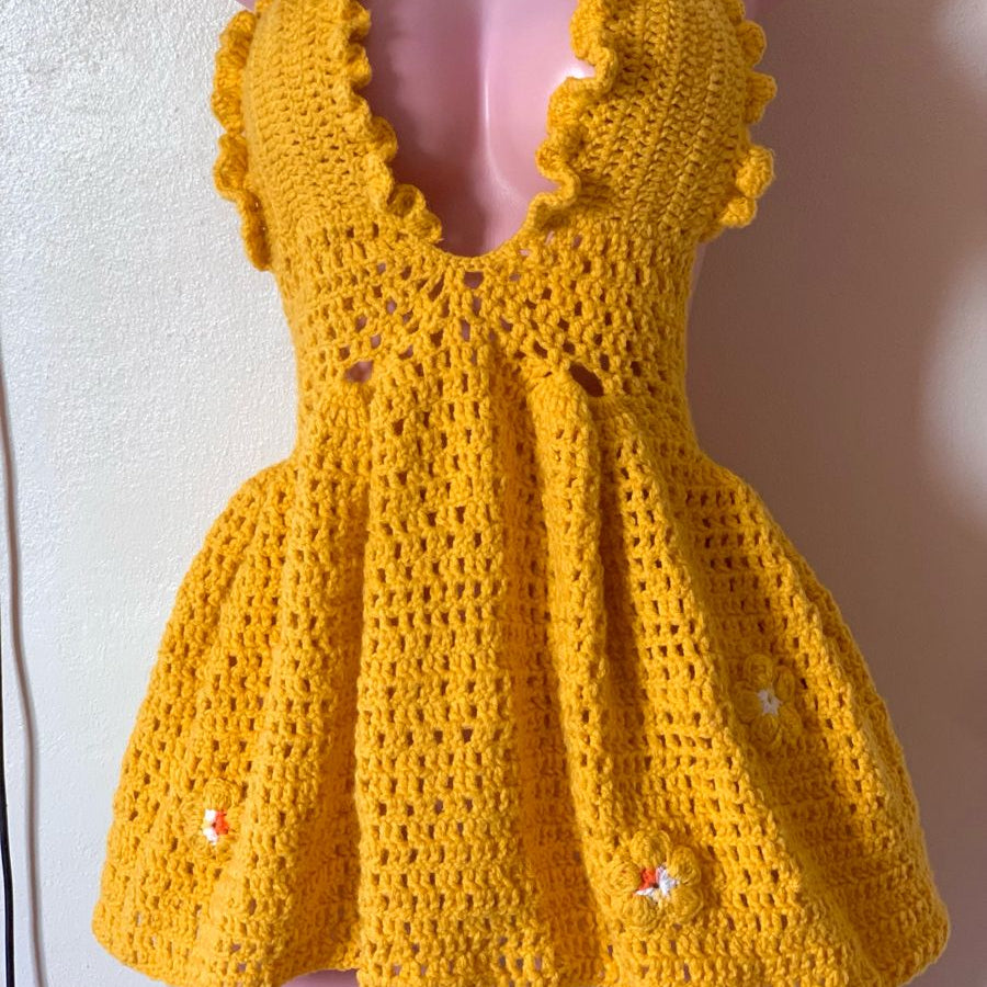 Yellow crochet dress on a mannequin against a plain background