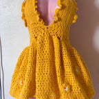 Yellow crochet dress on a mannequin against a plain background