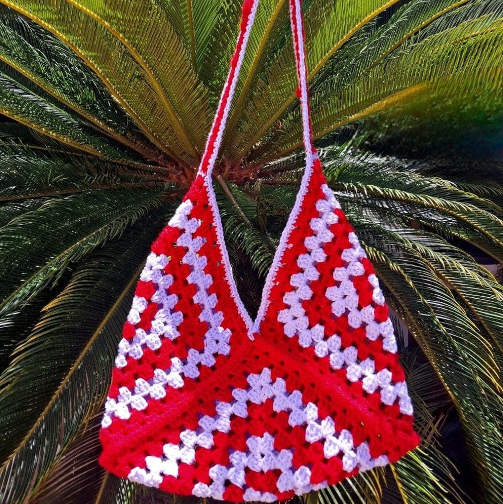 Red and white patterned bag against a green palm leaf background