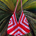 Red and white patterned bag against a green palm leaf background