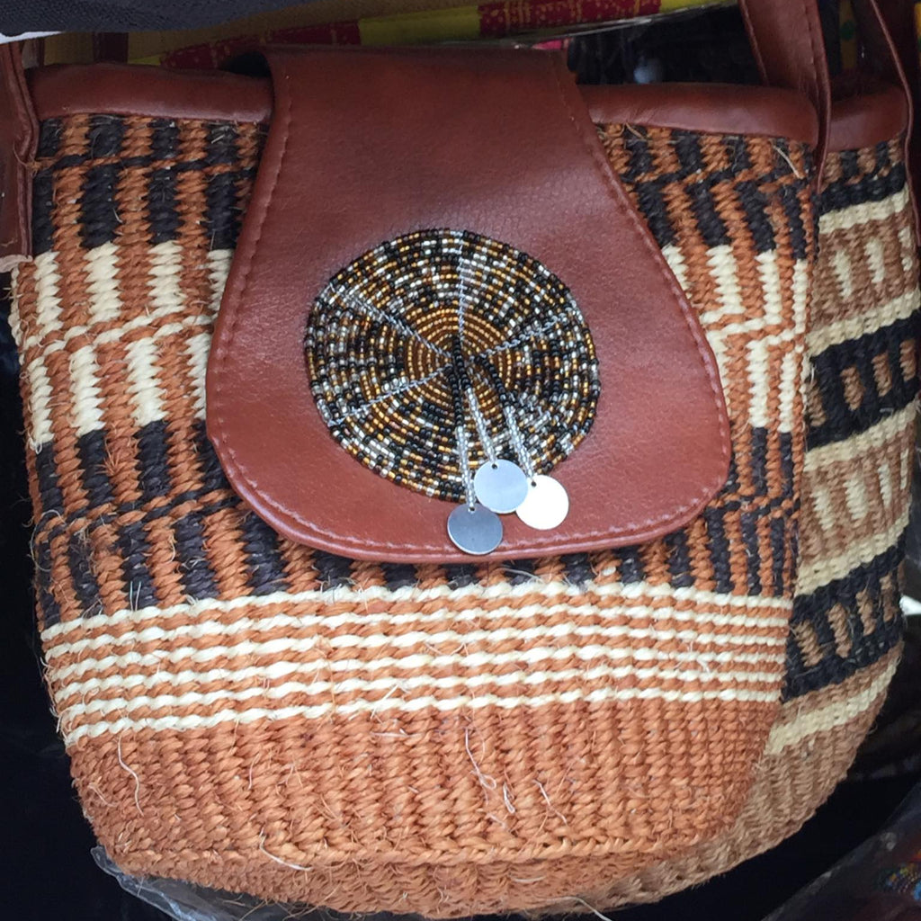 Brown woven bag with a decorative circular patch on a black background