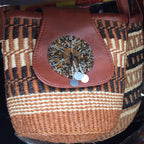 Brown woven bag with a decorative circular patch on a black background