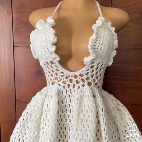 White crochet dress on a mannequin against a wooden background
