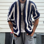 Person wearing a blue and white striped cardigan in front of a house.