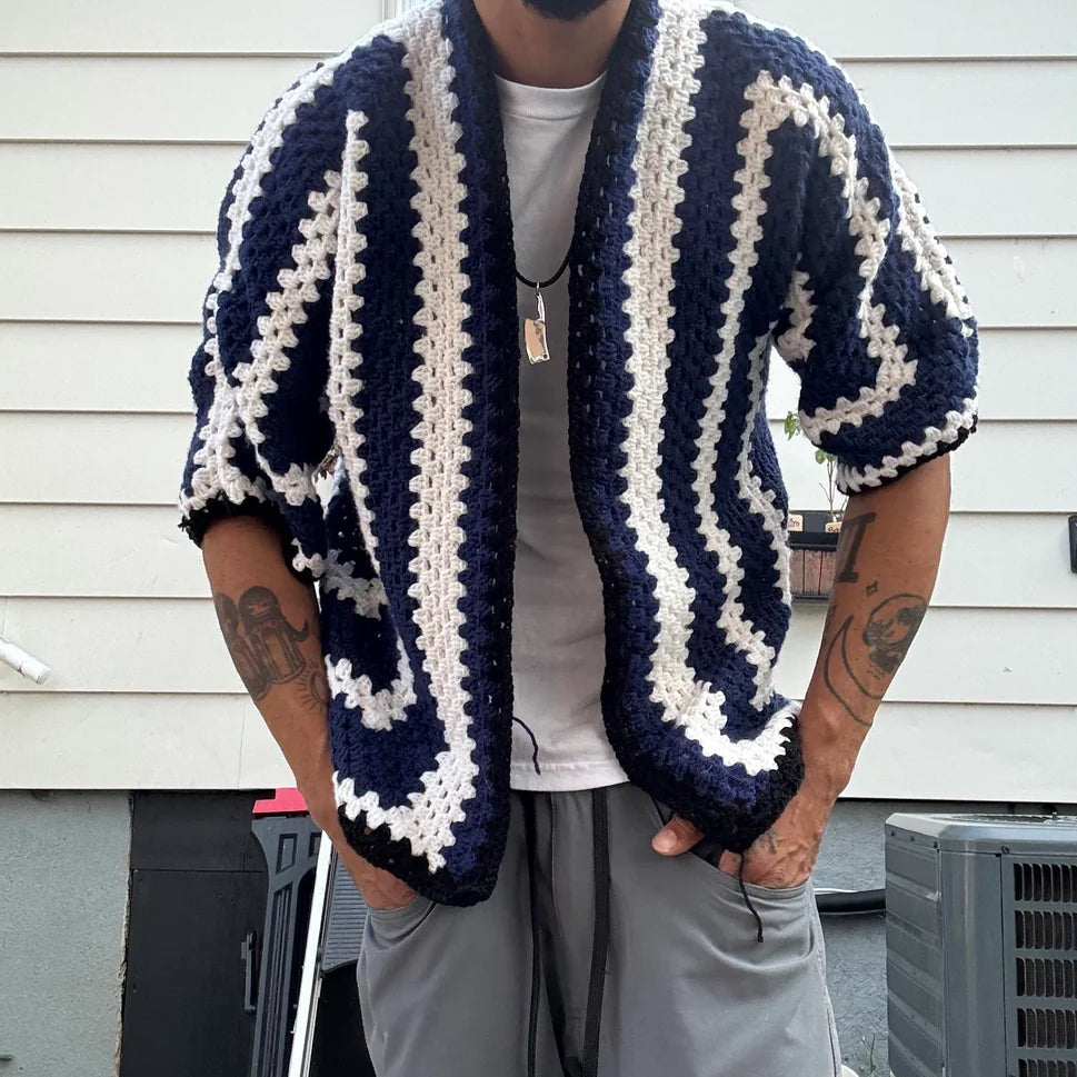 Person wearing a blue and white striped cardigan in front of a house.