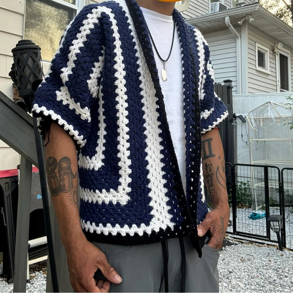 Person wearing a blue and white patterned cardigan with a house in the background