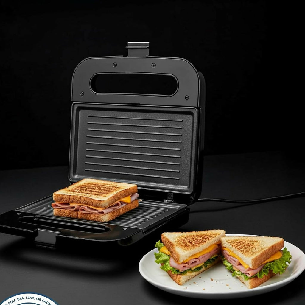Black sandwich maker with a toasted sandwich on a plate, PFAS-free ceramic cooking plates logo visible