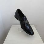 Black textured loafers on a white pedestal against a light gray background