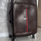 Brown suitcase with a red stripe on a gray floor against a textured wall.