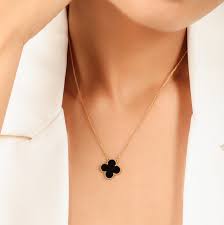 Gold necklace with a black clover pendant on a white background