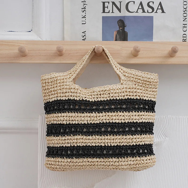 Woven bag with black and beige stripes hanging on a wooden rack.