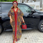 Woman in a patterned dress standing next to a black car