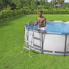 Man standing by a above-ground pool in a grassy area with trees in the background