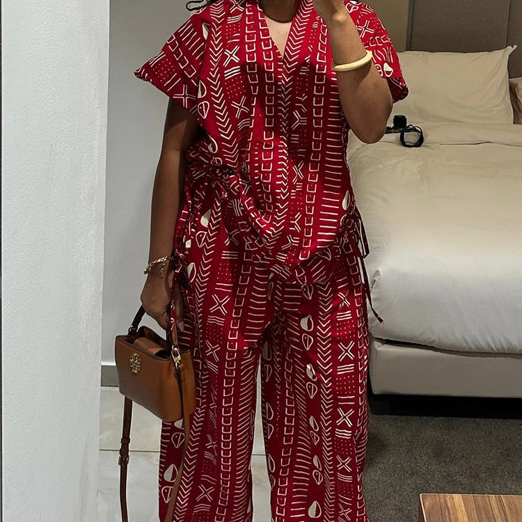 Person wearing a red patterned outfit taking a mirror selfie in a bedroom.