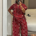 Person wearing a red patterned outfit taking a mirror selfie in a room.