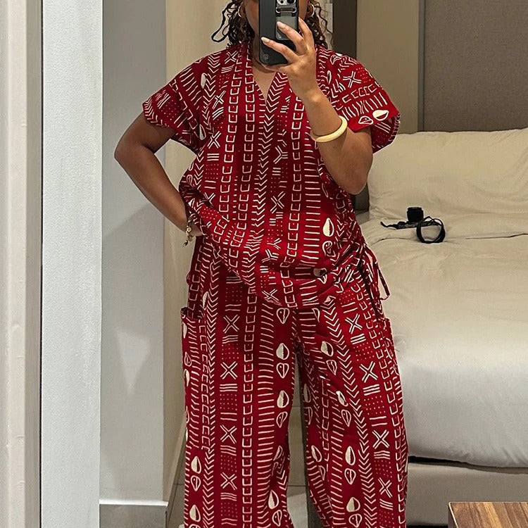 Person wearing a red patterned outfit taking a mirror selfie in a room.