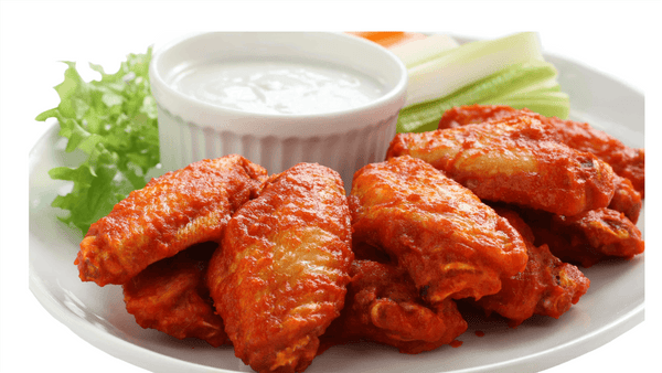 Platter of buffalo wings with a side of ranch dressing and celery sticks on a white background. mini Chicken wings from Town Bakery