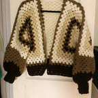 Brown and beige knitted sweater on a hanger against a white wall