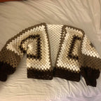 Crocheted sweater with brown and white pattern on a bed