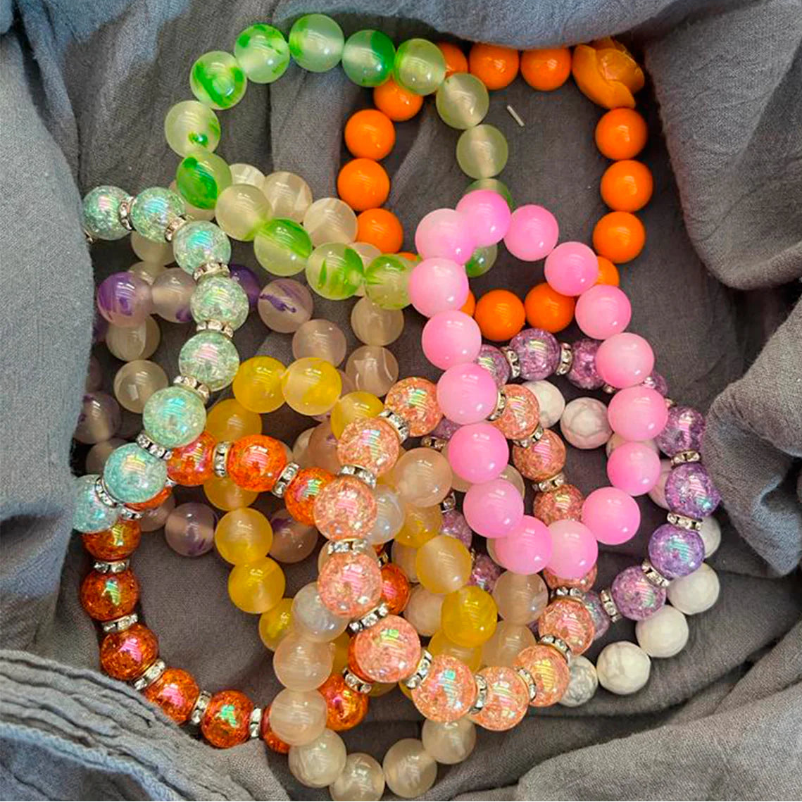 Colorful beaded bracelets on a gray fabric background